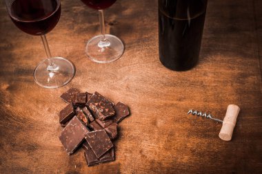 Kırmızı şarap ile bir tirbuşon bir şişe. Siyah bir ahşap arka plan üzerinde.