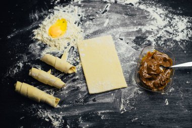 Malzemeler ve unlu mamüller - un, hamur, yumurta, oklava, çırpma teli, süzgeç, hazırlanması için mutfak eşyaları - ücretsiz kopya alanı siyah masada ekmek