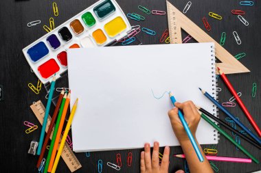 çocuğun çeşitli okul malzemeleri ile masada boş ders kitabı yazma kırpılmış görüntü