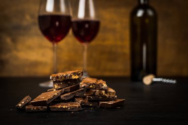 bir şişe şarap, çikolatalı dilimler ve iki bardak koyu arka plan üzerinde