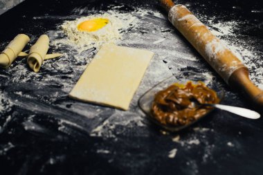 Malzemeler ve unlu mamüller - un, hamur, yumurta, oklava, çırpma teli, süzgeç, hazırlanması için mutfak eşyaları - ücretsiz kopya alanı siyah masada ekmek