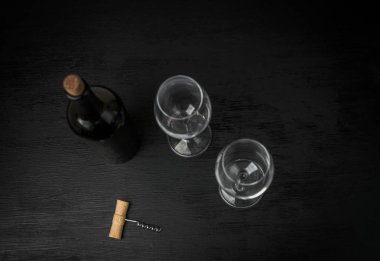 bir şişe şarap ve siyah arka plan üzerine iki boş bardak