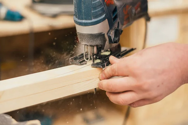 Man sanding a wood with sander in a workshop