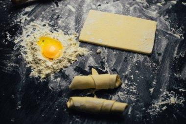 Malzemeler ve unlu mamüller - un, hamur, yumurta, oklava, çırpma teli, süzgeç, hazırlanması için mutfak eşyaları - ücretsiz kopya alanı siyah masada ekmek