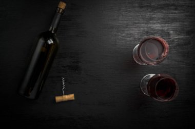 bir şişe şarap ve siyah arka plan üzerine iki boş bardak