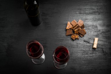 Kırmızı şarap ile bir tirbuşon bir şişe. Siyah bir ahşap arka plan üzerinde.