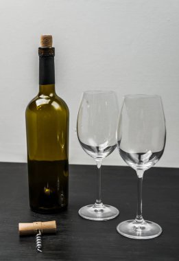 Bir şişe kırmızı şarap gözlük ile. Siyah bir ahşap arka plan üzerinde.