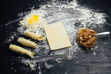 Malzemeler ve unlu mamüller - un, hamur, yumurta, oklava, çırpma teli, süzgeç, hazırlanması için mutfak eşyaları - ücretsiz kopya alanı siyah masada ekmek