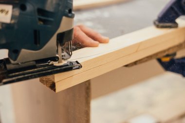 Man sanding a wood with sander in a workshop clipart