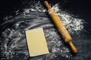 Malzemeler ve unlu mamüller - un, hamur, yumurta, oklava, çırpma teli, süzgeç, hazırlanması için mutfak eşyaları - ücretsiz kopya alanı siyah masada ekmek