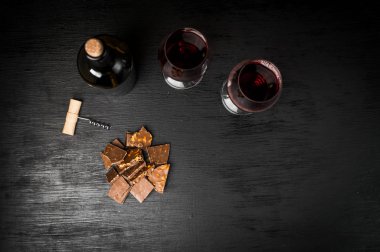 Kırmızı şarap ile bir tirbuşon bir şişe. Siyah bir ahşap arka plan üzerinde.