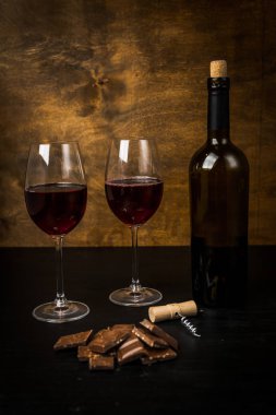 Kırmızı şarap ile bir tirbuşon bir şişe. Siyah bir ahşap arka plan üzerinde.
