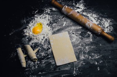 Malzemeler ve unlu mamüller - un, hamur, yumurta, oklava, çırpma teli, süzgeç, hazırlanması için mutfak eşyaları - ücretsiz kopya alanı siyah masada ekmek