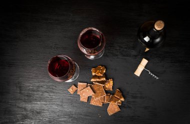 Kırmızı şarap ile bir tirbuşon bir şişe. Siyah bir ahşap arka plan üzerinde.