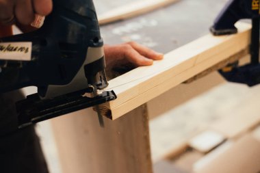 Adam atölyede zımpara ile odun zımparalıyor.