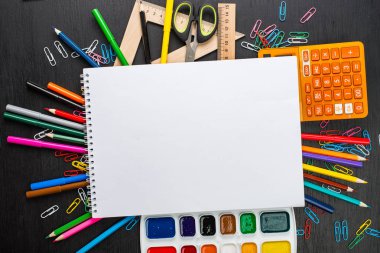 düz lay ile çeşitli okul malzemeleri siyah masada çevrili boş ders kitabı