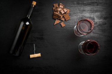 Kırmızı şarap ile bir tirbuşon bir şişe. Siyah bir ahşap arka plan üzerinde.