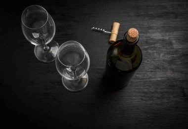 bir şişe şarap ve siyah arka plan üzerine iki boş bardak