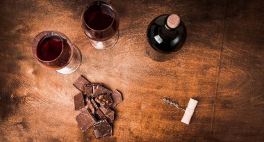 Kırmızı şarap ile bir tirbuşon bir şişe. Siyah bir ahşap arka plan üzerinde.