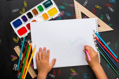 çocuğun çeşitli okul malzemeleri ile masada boş ders kitabı yazma kırpılmış görüntü