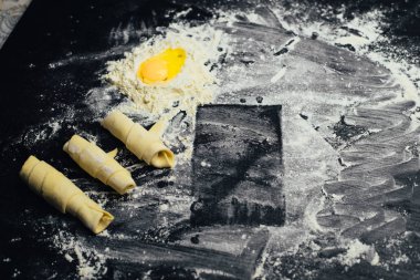 Malzemeler ve unlu mamüller - un, hamur, yumurta, oklava, çırpma teli, süzgeç, hazırlanması için mutfak eşyaları - ücretsiz kopya alanı siyah masada ekmek