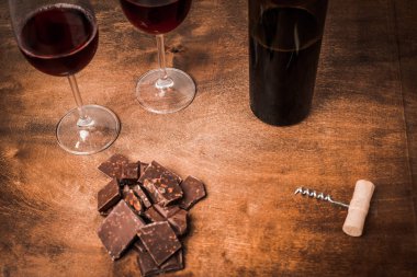 Kırmızı şarap ile bir tirbuşon bir şişe. Siyah bir ahşap arka plan üzerinde.