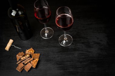 Kırmızı şarap ile bir tirbuşon bir şişe. Siyah bir ahşap arka plan üzerinde.