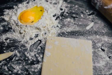 Malzemeler ve unlu mamüller - un, hamur, yumurta, oklava, çırpma teli, süzgeç, hazırlanması için mutfak eşyaları - ücretsiz kopya alanı siyah masada ekmek