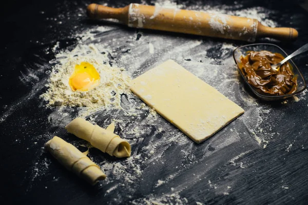Malzemeler ve unlu mamüller - un, hamur, yumurta, oklava, çırpma teli, süzgeç, hazırlanması için mutfak eşyaları - ücretsiz kopya alanı siyah masada ekmek