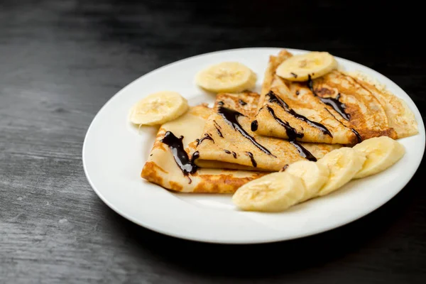 Delicious pancakes with banana and chocolate on plate