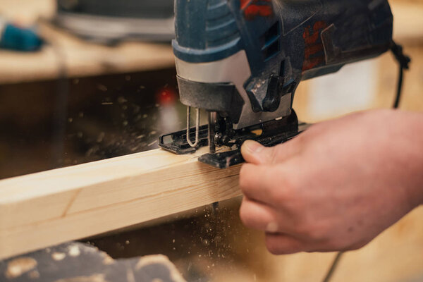 Man sanding a wood with sander in a workshop