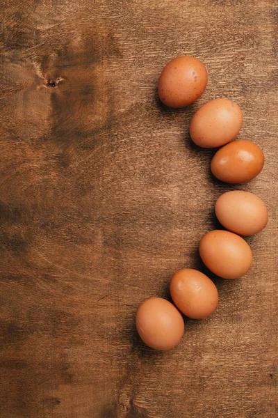 Brown eggs lying on wooden background