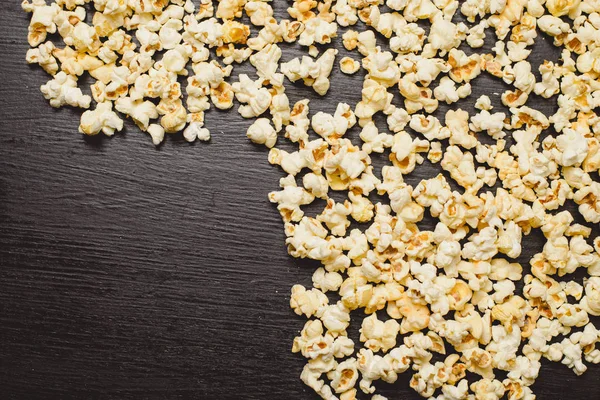  siyah arka plan üzerine tuzlu patlamış mısır. Üstten görünüm.