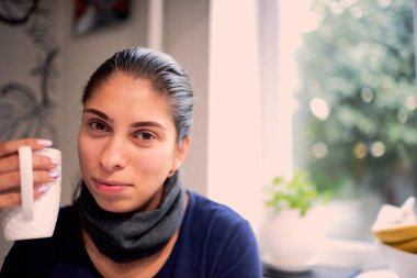 kafede otururken kameraya bakarak kahve fincanı ile gülümseyen kadın portresi 