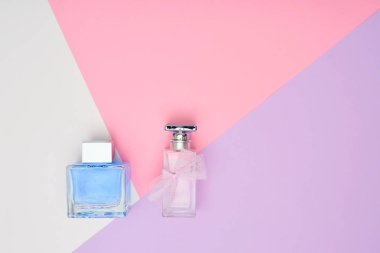 Pastel arka plan üzerinde parfüm şişeleri. En az stili.