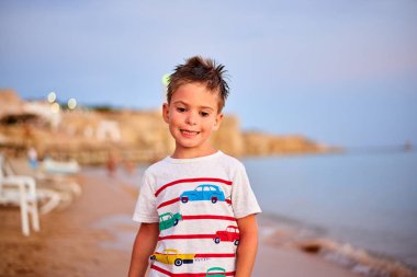 neşeli küçük çocuk kumsalda tatil sırasında ayakta önden görünümü 