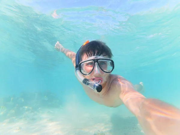 happy man in diving mask taking selfie while swimming under water