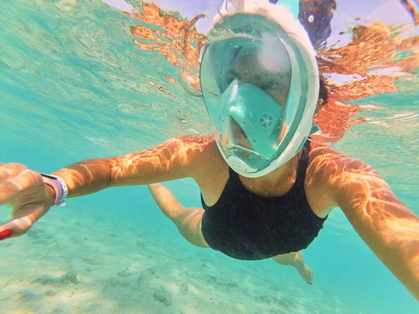 woman in diving mask taking selfie while swimming under water