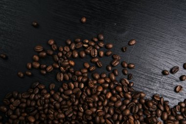 kavrulmuş aromatik kahve çekirdekleri üstten görünüm siyah ahşap yüzey üzerinde