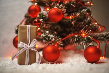 hediye kutusu kırmızı parlak topları ve ışıklı garland ile Noel ağacı altında 