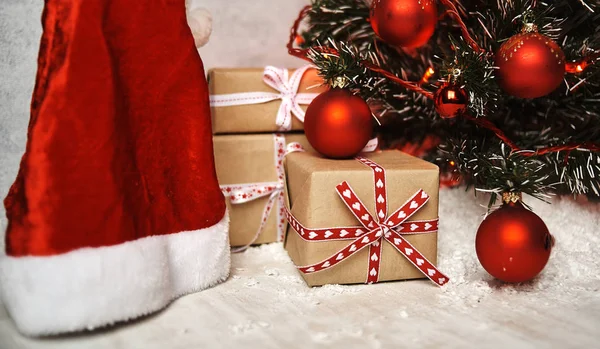 gift boxes and santa hat under christmas tree with beautiful shiny decorations