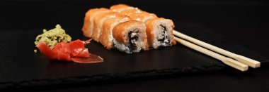 philadelphia rulo wasabi, yemek çubukları ile görünümünü kapatın ve ahşap masa zencefil