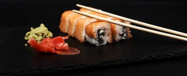 philadelphia rulo wasabi, yemek çubukları ile görünümünü kapatın ve ahşap masa zencefil