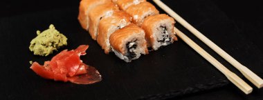 philadelphia rulo wasabi, yemek çubukları ile görünümünü kapatın ve ahşap masa zencefil