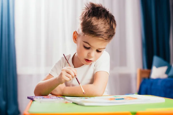 little child drawing by painting brush at table