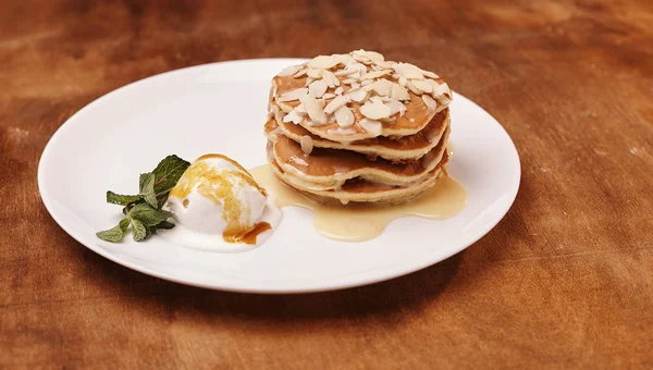 tasty pancakes with almond flakes ice cream on plate