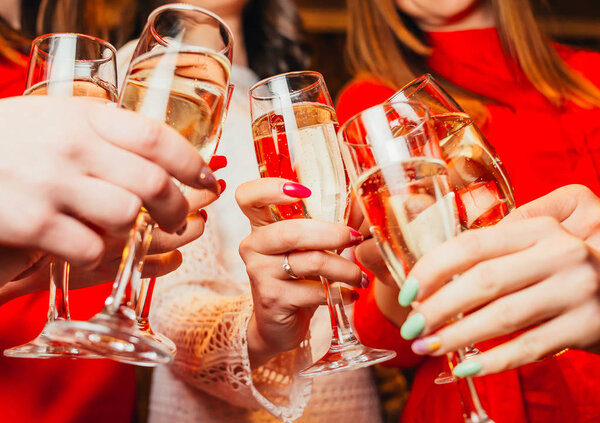 Группа подруг, празднующих и звенящих с бокалами шампанского
 