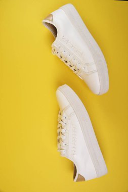 Sarı arka planda beyaz şık spor ayakkabıları