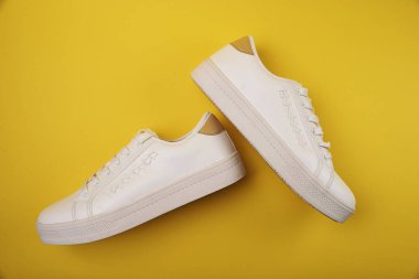 Sarı arka planda beyaz şık spor ayakkabıları