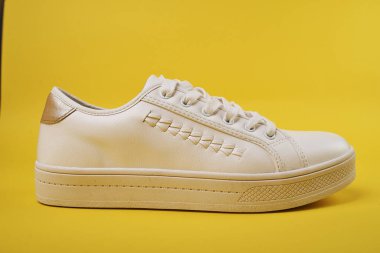 Sarı arka planda beyaz şık spor ayakkabıları